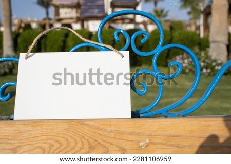 top of park bench with white hanging picture sign with empty free space for template or blank copy area