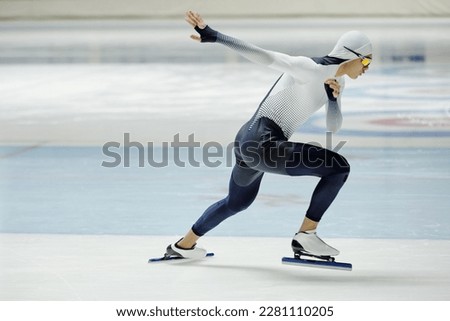 Side view of young active man in sports uniform and skates practicing exercises on ice rink while preparing for important competition