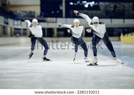 Group of young male athletes in sports uniform speed skating on ice rink with one of them sliding in front during competition or training