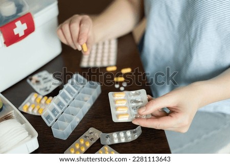 Closeup female hand neatly placing medicament at domestic first aid kit top view. Storage organization in transparent plastic box drug, pill, syringe, bandage. Fast health help safety emergency supply Royalty-Free Stock Photo #2281113643