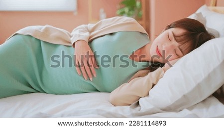 closeup asian pregnant woman laying on the bed happily taking a rest and enjoying motherhood moment with smile Royalty-Free Stock Photo #2281114893