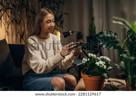 Young blonde woman florist taking picture of plants she replanted