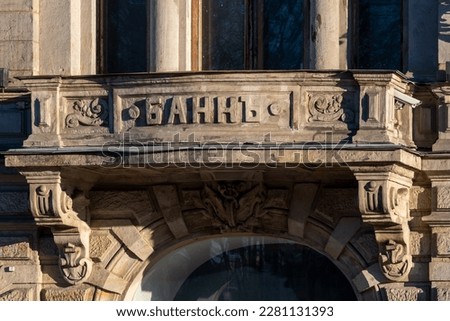 Old russian Bank word on ornate stone building facade above entrance in a sunny day. Soft focus. Russian business and finance theme.