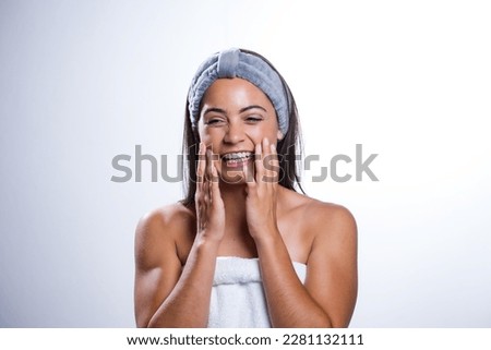 A stunning young woman takes care of her skin and beauty with a daily routine. Shot in a studio on a white background, her natural beauty radiates.
