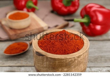Bowl with aromatic paprika powder on wooden table, closeup Royalty-Free Stock Photo #2281142359