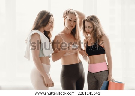 Three beautiful sporty girls looking at smartphone after home fitness training Royalty-Free Stock Photo #2281143641