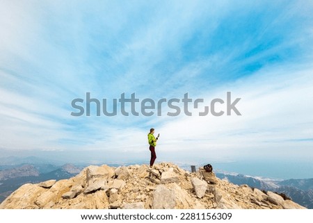 climber on top of the mountain takes a photo. Woman traveler takes a photo on a modern smartphone, makes beautiful pictures of beautiful mountain landscapes. mountain climbing and adventure.
