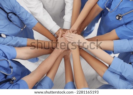 Doctor and interns stacking hands together indoors, above view