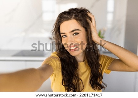 Picture of young smiling beautiful positive ginger woman indoors at home take selfie by camera.