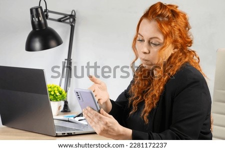 Office worker. The girl at the laptop in the office. Business woman doing work talking on the phone.
