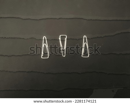 three paper clips placed on black paper