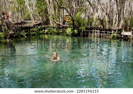 Pretty young caucasian female tourist swimming in El Corchito Ecological Reserve, Progreso, Mexico during sunny day. Eco concept.