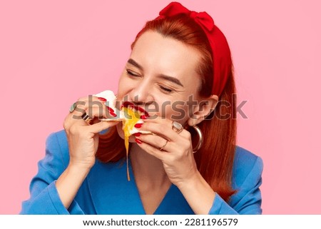 Close-up portrait of young redhead woman eating fried eggs against pink studio background. Liquid yolk. Food pop art photography. Breakfast. Complementary colors. Copy space for ad, text