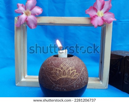 wooden picture frame square box in gradient blue background with flower head Adenium beautiful red pink tropical flower called desert rose and candle holder still life concept. Selective focus