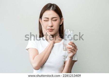 Suffering from toothache, blur asian young woman touch cheek, face expression ache or feel pain, sensitive molar teeth, hand holding glass of water with ice, inflammation when drink cold, healthcare. Royalty-Free Stock Photo #2281213409