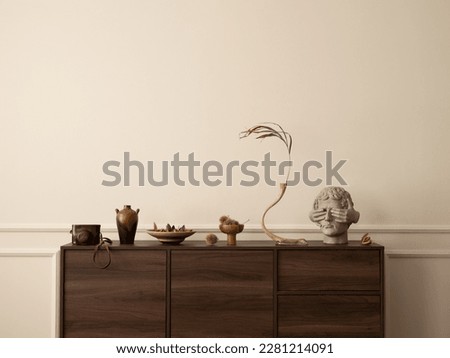 Aesthetic composition of living room interior with wooden sideboard, glass vase with dried flowers, modern sculpture, nuts, wall with stucco and personal accessories. Home decor. Template. Royalty-Free Stock Photo #2281214091