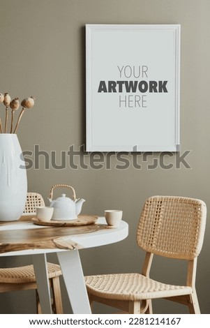 Cozy and stylish interior of kitchen space with wooden table with white mock up photo frame, design cups and rattan chairs. Scandinavian room decor with kitchen accessories and decoration. Home decor