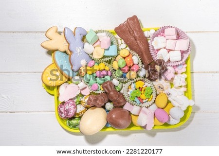 Easter charcuterie board. Sweet Easter party, kids holiday treats assortment - chocolates, easter eggs, marshmallows, candies, chocolate bunny, snacks and treats tray
