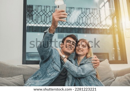 a couple sitting on the sofa relaxing with a cell phone selfie