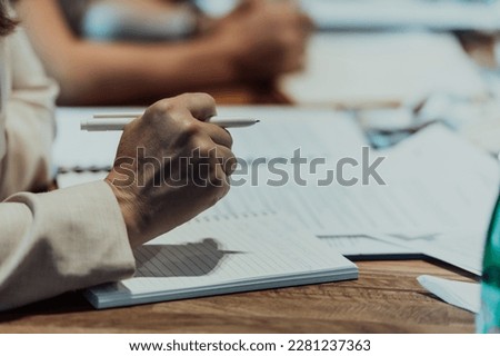 Closeup shot of business people hands using pen while taking notes on education training during business seminar at modern conference room