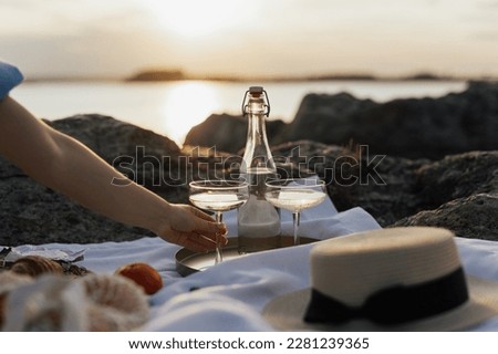 Cropped picture of a woman sitting on a picnic at nature. Concept of having picnic on shore of the sea at sunset the during summer holidays or weekends. 