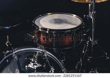 Snare drum on a blurred dark background, part of a drum kit.