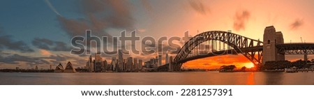 Sydney Harbour Bridge, Opera House and skyscrapers in the city are shrouded in pink afterglow under the reflection of the setting sun. Royalty-Free Stock Photo #2281257391