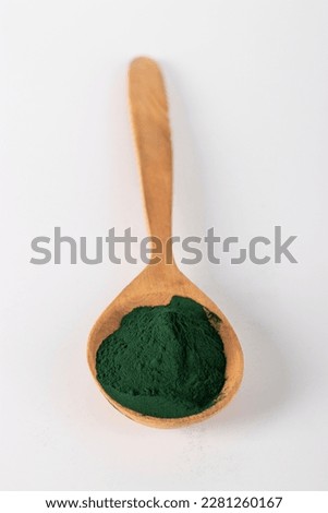 Organic spirulina algae powder in wooden spoon on white background. Close-up