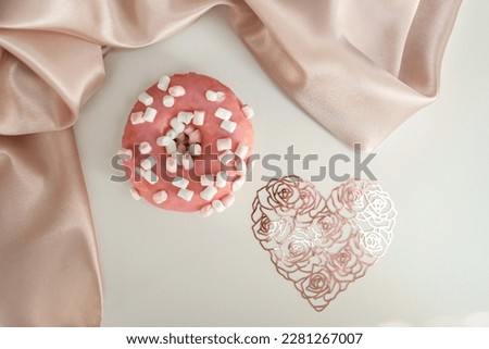 Donut with splashes, on a white background, with a lace heart and silk fabric, delicate picture