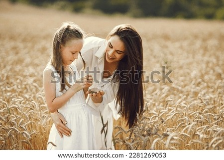 Mother and daughter both in white dresses at the wheat field