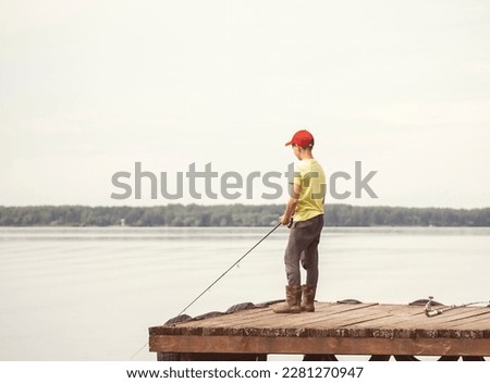 A teenager is fishing in the river. Recreation Concept, Summer, Mental Health.