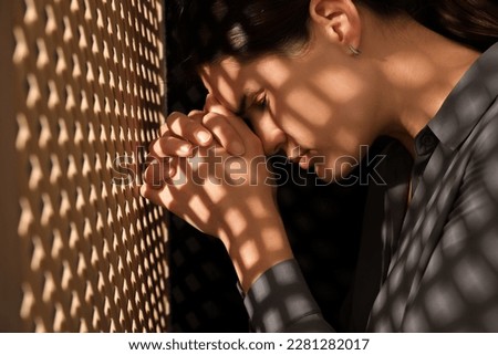 Repentant woman during confession near wooden partition in booth Royalty-Free Stock Photo #2281282017