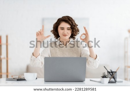 curly sign language teacher showing alphabet letters during online lesson on laptop