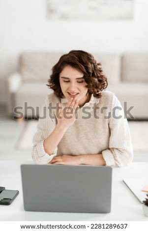 young sign language teacher smiling while showing thank you gesture during online lesson on laptop at home