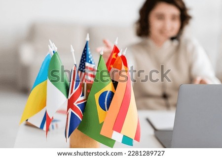 selective focus of various international flags near blurred laptop and language teacher having online lesson at home Royalty-Free Stock Photo #2281289727