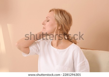 Woman suffering from hormonal disorders near beige wall indoors Royalty-Free Stock Photo #2281296301