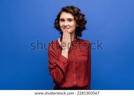 carefree woman looking at camera and telling thank you on sign language isolated on blue Royalty-Free Stock Photo #2281303567