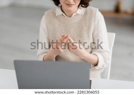 partial view of smiling teacher showing British two handed sign alphabet during online lesson