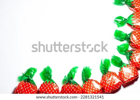 Wrapped candies with strawberry pattern isolated on white background. Top view frame of candies. Unhealthy food, snack idea concept. Copy space. No people. Above, blank. Empty area.