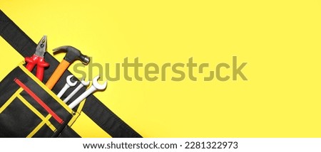 Belt bag with construction tools on yellow background with space for text