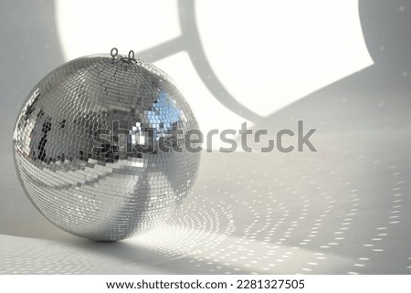 A mirror ball with sunbeams on a photo studio cyclorama. Natural light with shadows. Space for text. 