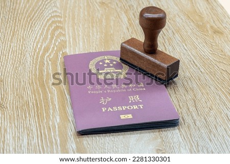 A Chinese passport on a wooden table, symbolize an upcoming trip and the Republic's identity card.
