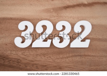 White number 3232 on a brown and light brown wooden background.