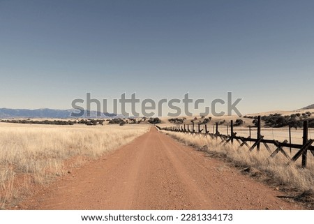 A lonely dirt road through the grasslands along the border between the United States and Mexico in Arizona. Royalty-Free Stock Photo #2281334173