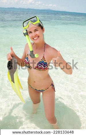 Happy woman snorkeling  and having fun in water holding fins 