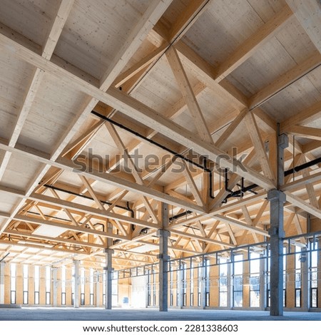 modern industrial hall with timber trusses and prefabricated concrete columns with many glass facade elements Royalty-Free Stock Photo #2281338603
