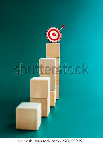 Goal and success. Arrow dart on 3d target icon on top of wooden cube blocks, bar graph steps, vertical. Business growth process, development, leadership, marketing, economic improvement concepts.