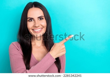 Photo portrait of charming toothy smiling beautiful lady brunette hair pointing finger empty space good news isolated on aquamarine color background