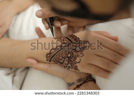 Decorating women's hands with paintings with tendrils or called Henna.