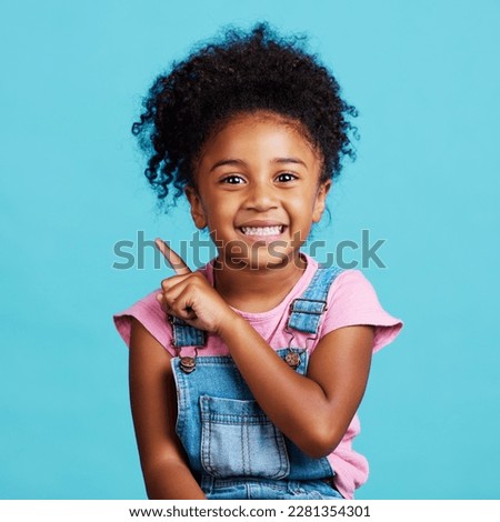 Portrait, pointing and mockup with a girl on a blue background in studio showing product placement space. Kids, marketing and advertising with an adorable female child indoor to point at branding Royalty-Free Stock Photo #2281354301